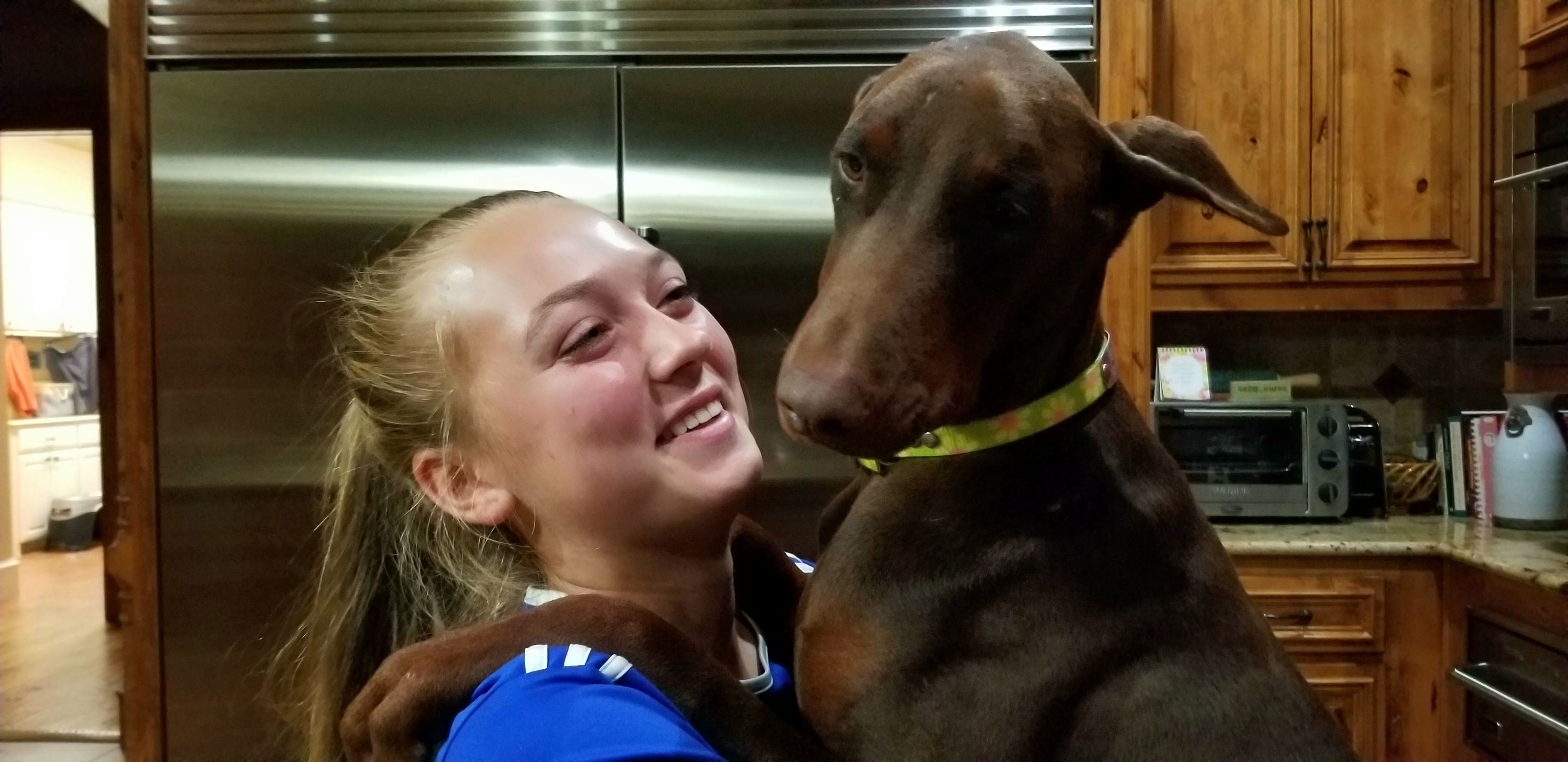 red rust female doberman and teenage daughter holding big pup